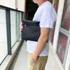 A person holds a black PU leather clutch bag for phone and card storage in a hallway setting.