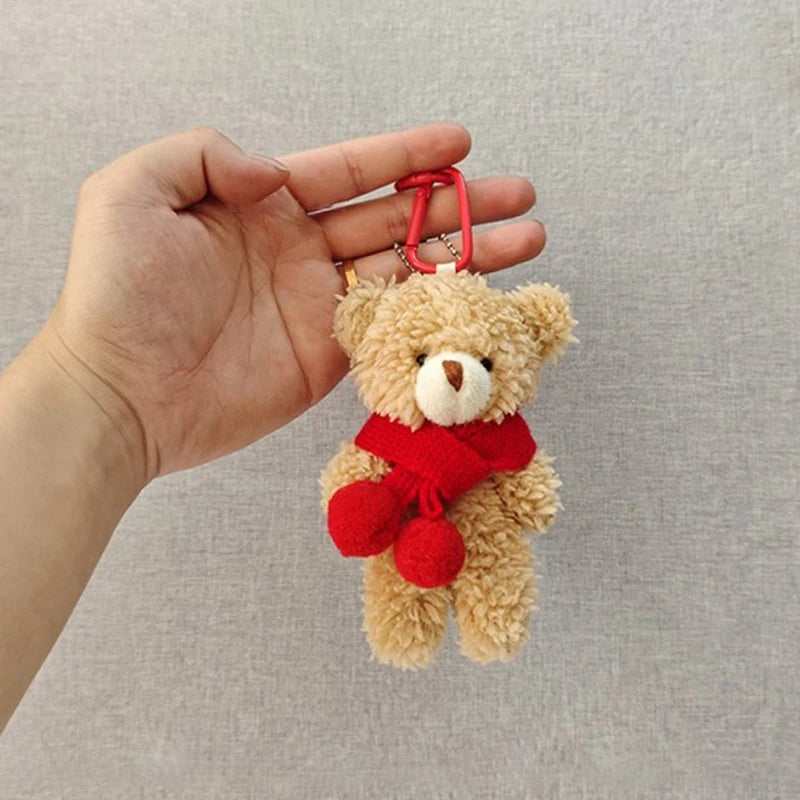 A fluffy brown teddy bear keychain featuring a red scarf and camera/glasses attached to a keyring.