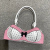 A pink and white polka dot bow shoulder bag with a playful bra silhouette and silver hardware.