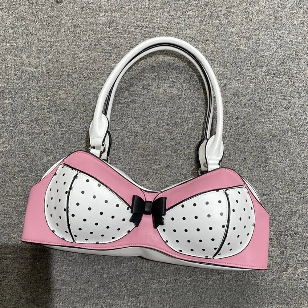 A pink and white polka dot bow shoulder bag with a playful bra silhouette and silver hardware.