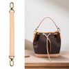 A black leather handbag with a light pink lining and a tan leather strap is displayed on a wooden surface.