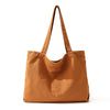 A brown canvas shoulder tote bag with long handles is shown against a white background.