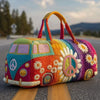 A colorful quilted travel duffle bag with a sunflower and peace sign design resting on asphalt.