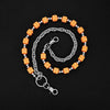 A silver chain necklace featuring square orange dice as charms, coiled in a circular pattern.
