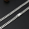 A silver punk charm bracelet with a chain and padlock clasp laid diagonally on a dark surface.