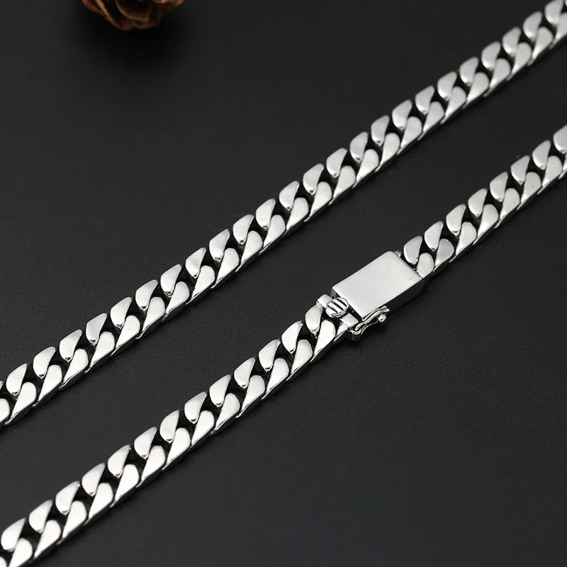 A silver punk charm bracelet with a chain and padlock clasp laid diagonally on a dark surface.