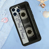 A black phone case featuring a vintage cassette tape design with a transparent window and silver accents.