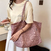 A woman holds a pink leopard print canvas tote bag against a white shirt in a bright indoor setting.