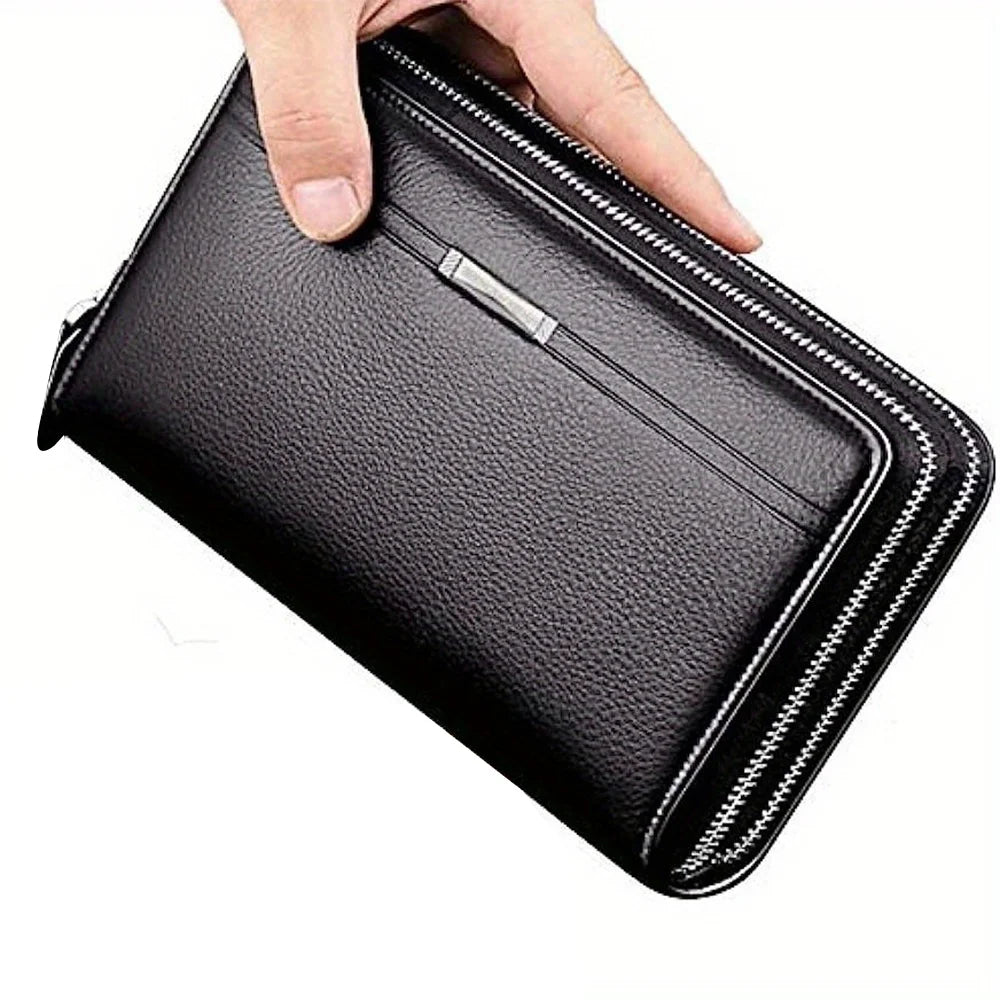 A hand is holding a black leather long zipper wallet clutch with silver accents.