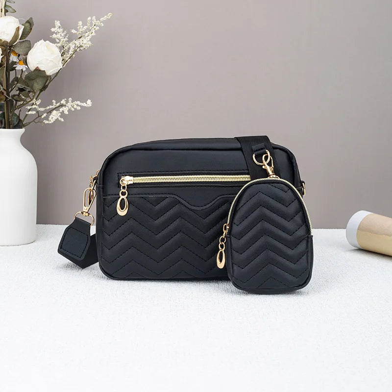 Schwarze gesteppte Crossbody-Tasche mit goldfarbenem Verschluss auf weißem Untergrund.