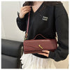 A woman holds a burgundy crocodile-embossed PU leather clutch bag against a black shirt.
