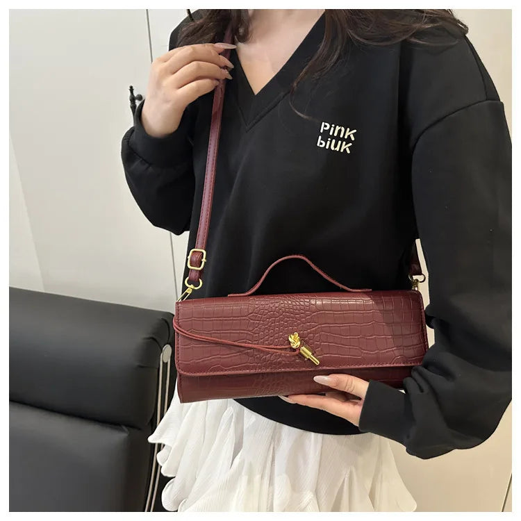 A woman holds a burgundy crocodile-embossed PU leather clutch bag against a black shirt.