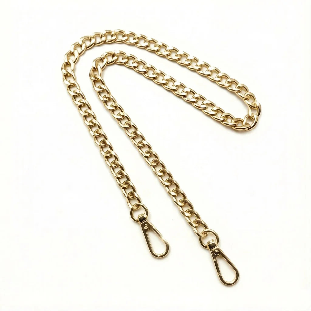 A gold-colored metal chain crossbody strap laid out against a white background.