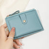 A hand holds a light blue ultra-thin PU leather card holder wallet with a gold zipper and silver accent.