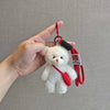 A white plush bear keychain featuring a camera and glasses attached to a red cord.