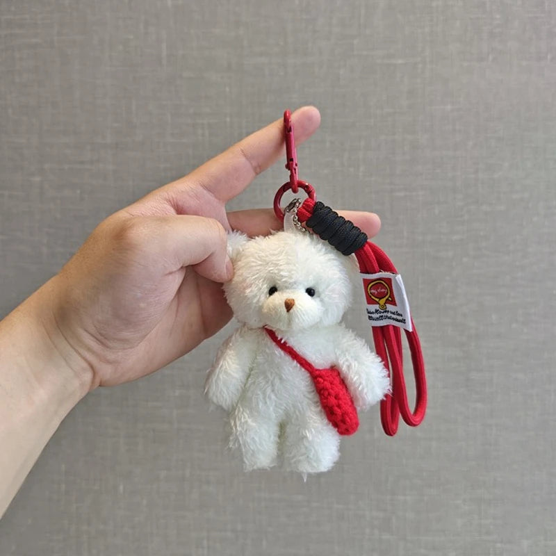 A white plush bear keychain featuring a camera and glasses attached to a red cord.