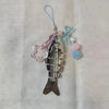 Silver simulation fish keychain with pink and blue accents on a clear cord