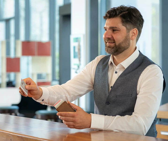 A man is holding a genuine leather RFID blocking card wallet in his hand.