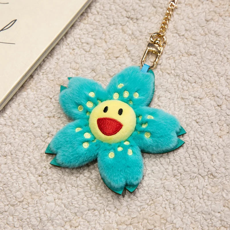 A bright turquoise sunflower plush keychain with yellow center and gold chain