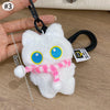 Colgante llavero de peluche de gato blanco esponjoso con ojos azules y una cinta rosa contra un fondo de madera.
