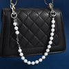 A black quilted leather bag with a gold chain and a long strand of white pearls.