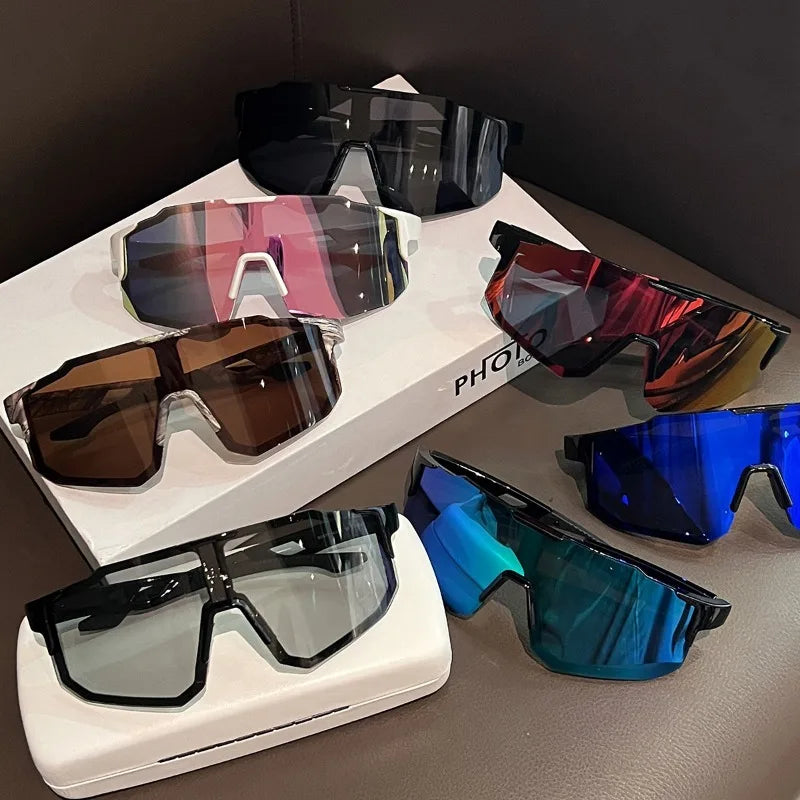 Colección de gafas de ciclismo UV400 de varios colores para hombres y mujeres, exhibidas sobre una superficie.