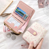 A pink cat cartoon coin purse and card holder wallet with a gold zipper and a pink leather cover is shown on a white surface.