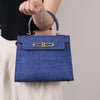 A navy blue crocodile pattern tote bag with gold hardware carried by a woman.