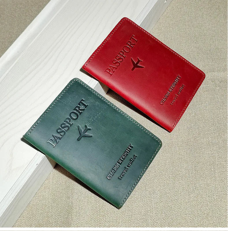 A red leather passport holder and a dark green leather passport wallet are displayed on a light surface.