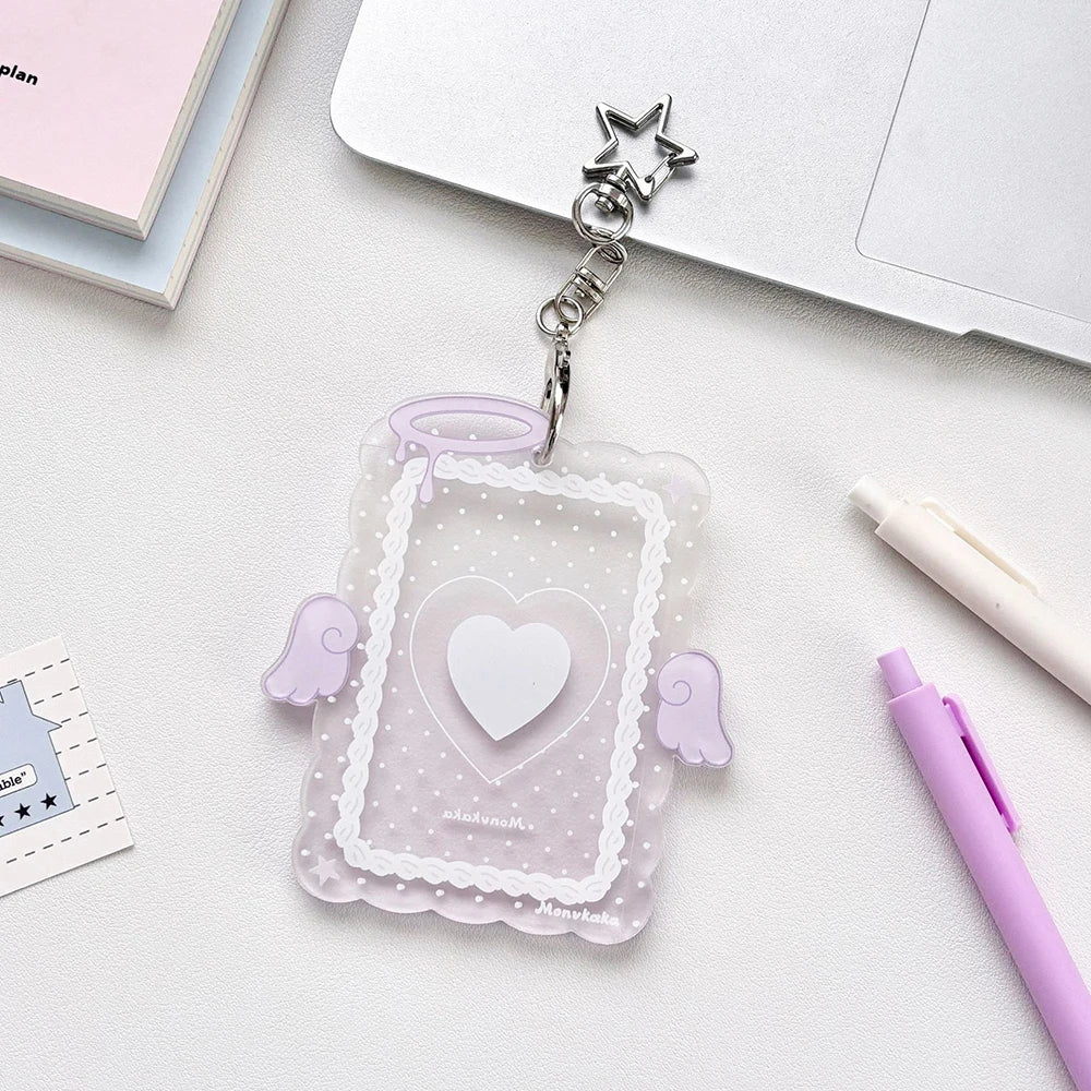 Clear acrylic photocard holder with a heart design and angel wings attached to a silver charm.