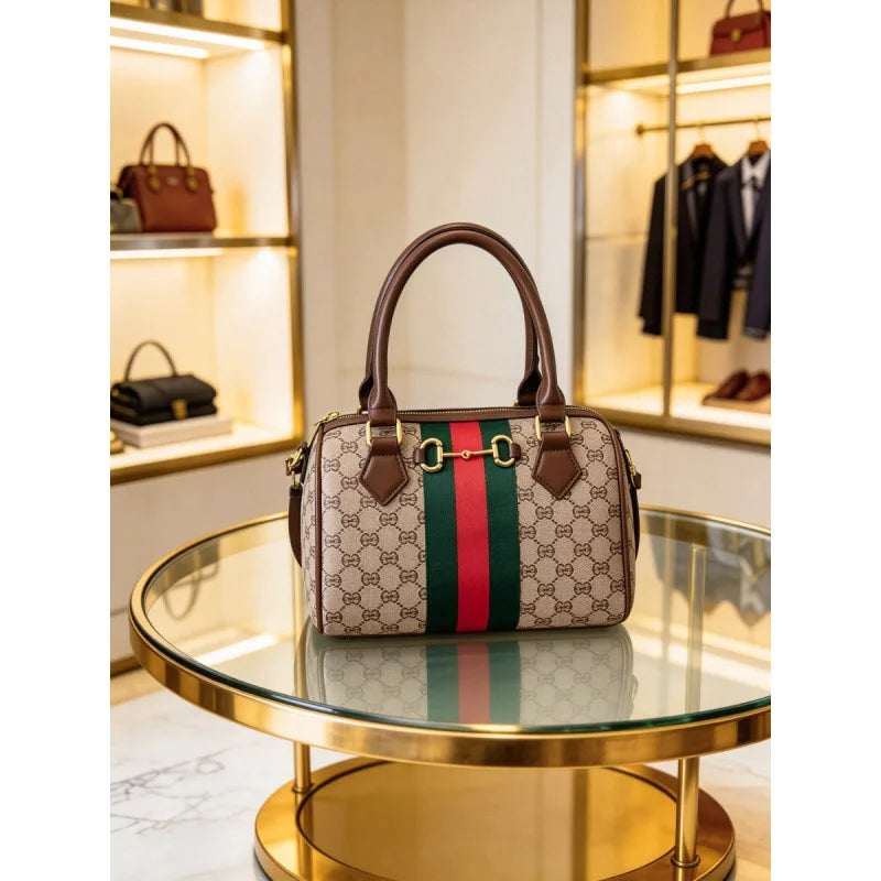 A brown and green patterned leather tote bag displayed on a glass table with gold accents.