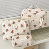 A beige striped cosmetic makeup bag with a light pink lining and bear embroidery is displayed on a white surface.