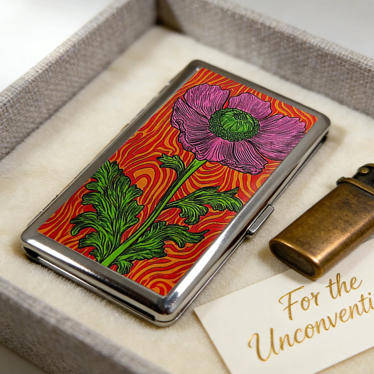 An Art Deco metal card case with a vibrant floral design rests in a light gray box.