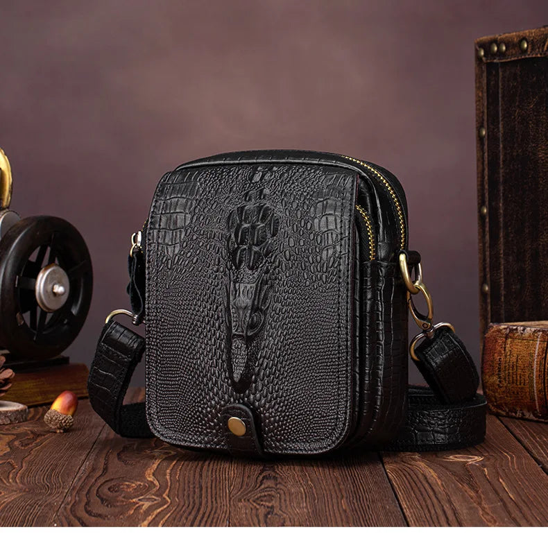 Black genuine cow leather crossbody bag for men resting on a wooden surface.