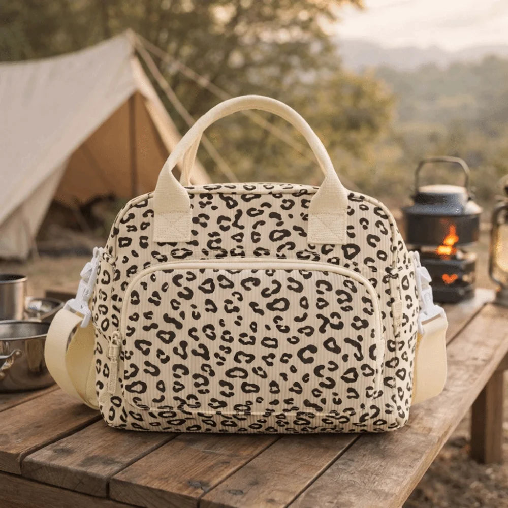 Sac de pique-nique portable à rayures beige en velours côtelé posé sur une surface en bois à l'extérieur.