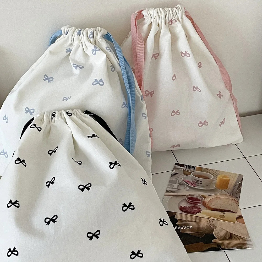 White canvas makeup bags with pink and blue accents featuring small bowknot designs.