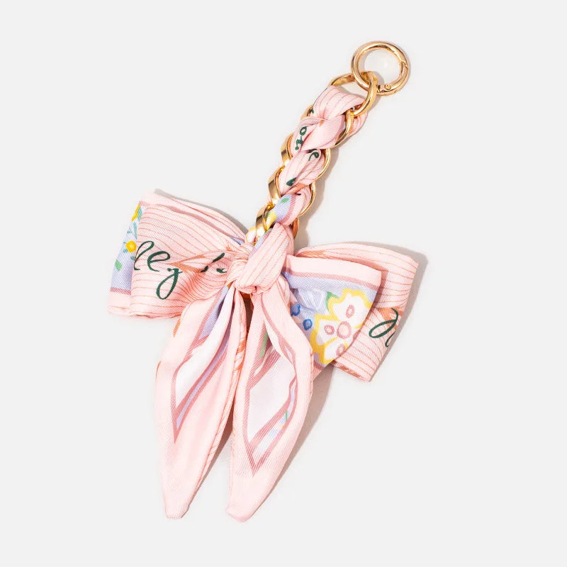 Pink and white striped fabric bow with a gold chain strap extension for a handbag