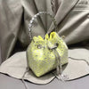 A yellow crystal-embellished evening clutch with a silver chain strap is displayed on a light gray fabric.