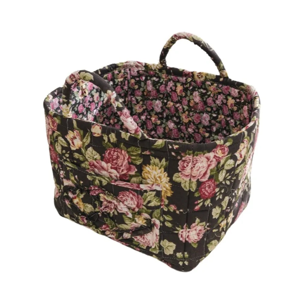 A dark floral quilted fabric storage basket with handles.