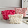 Two plush heart-pattern storage bags in pink and cream resting on a white surface.
