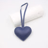 A dark blue PU leather heart-shaped keychain hanging from a white cylindrical object.
