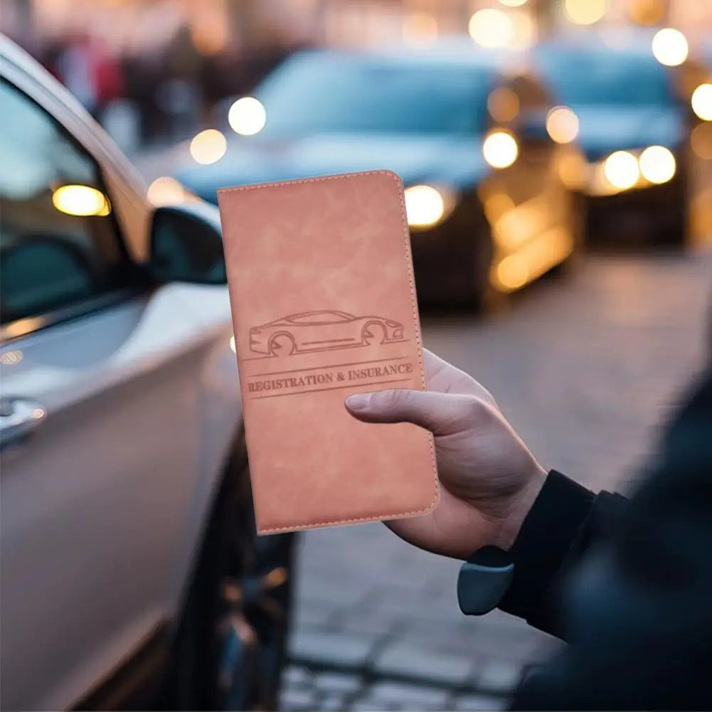 A hand holds a brown PU leather document organizer with a car silhouette on it next to a parked car.