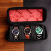 A black watch organizer case with a red velvet lining, holding three wristwatches.