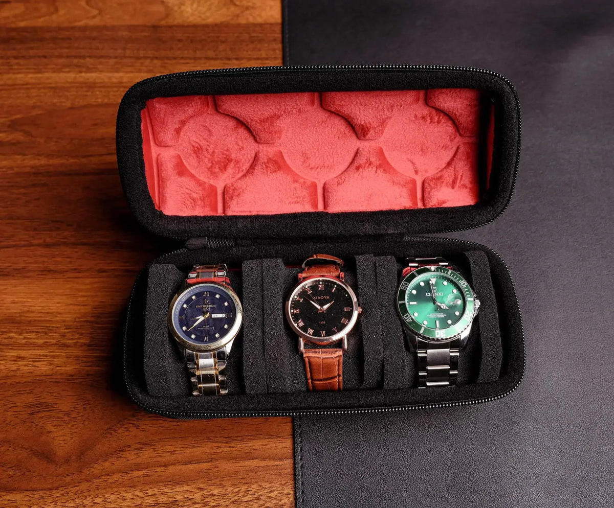 A black watch organizer case with a red velvet lining, holding three wristwatches.