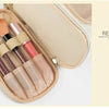 A beige travel pouch containing various makeup brushes and tools.