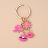 Gold-toned enamel keychain featuring a pink flower and pink lips on a gold ring.