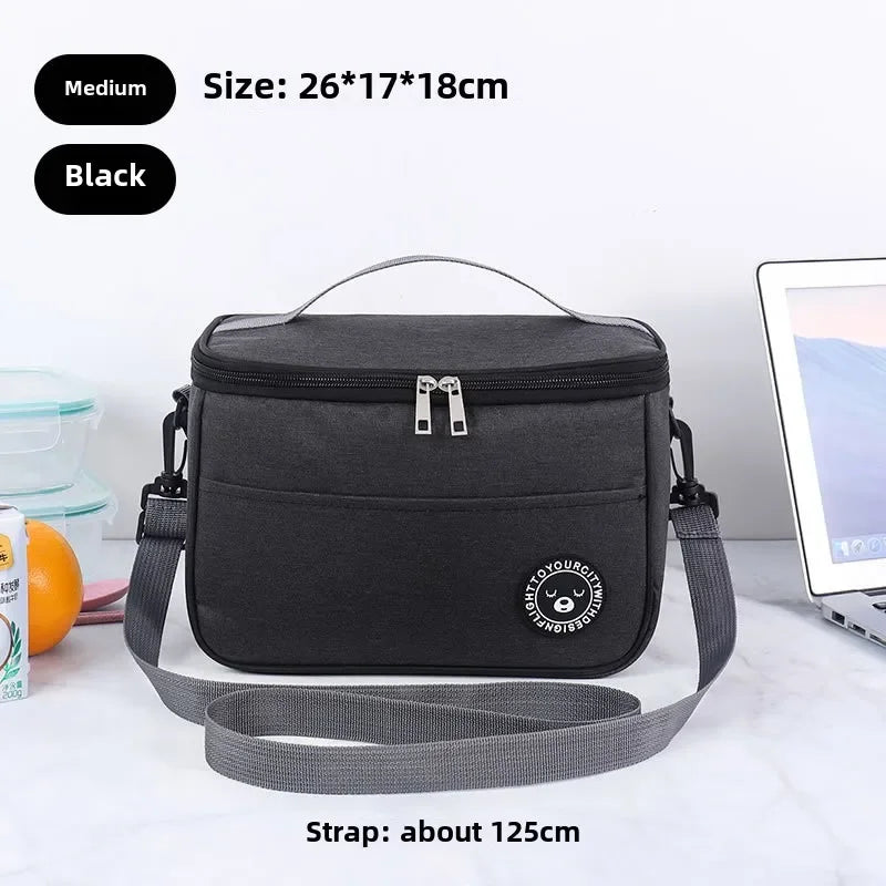 Black insulated portable lunch bag with a shoulder strap shown on a white surface.