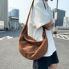 A person is holding a brown corduroy casual crossbody shoulder bag while standing in an outdoor parking lot.