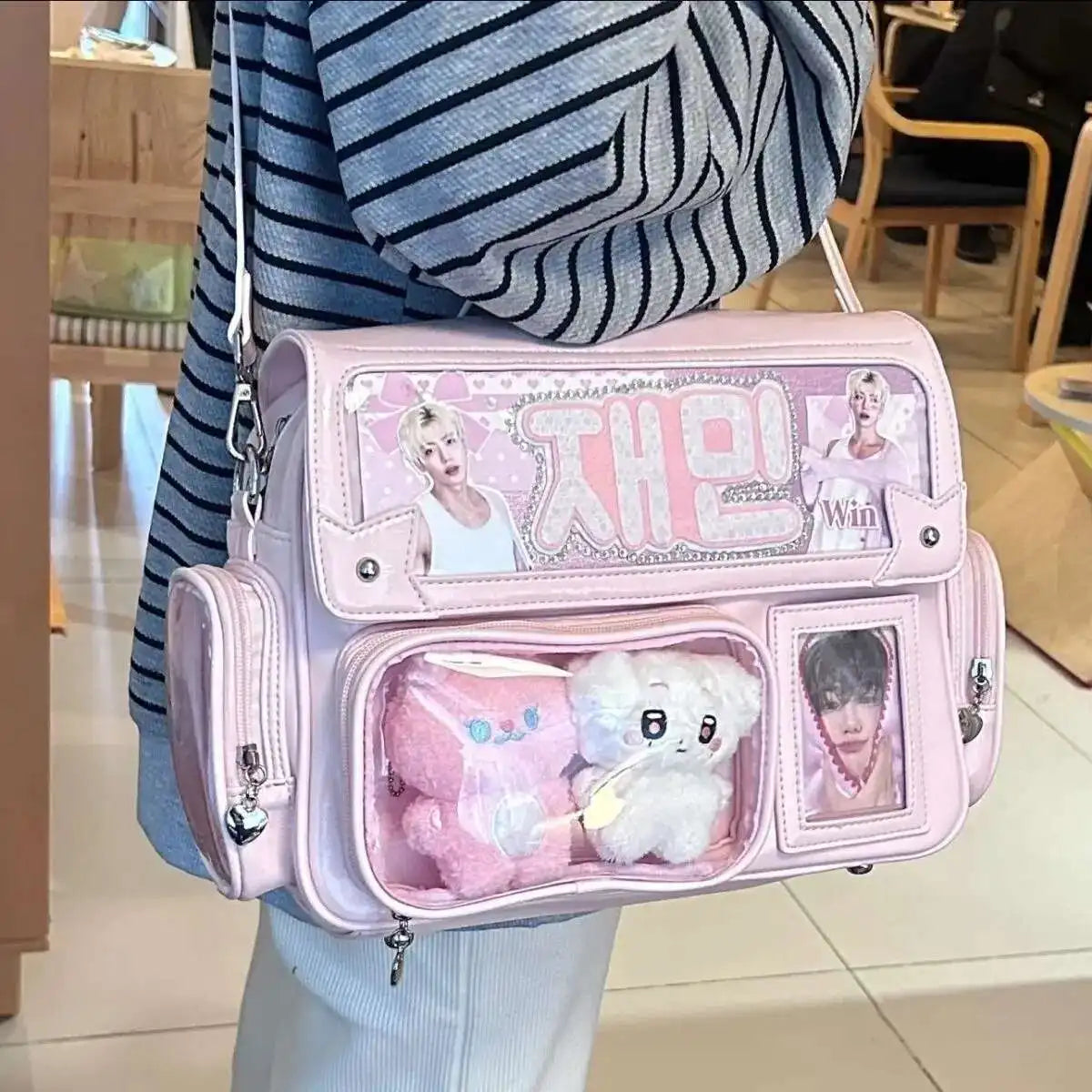 A pink transparent PU crossbody bag with cute animal charms worn by a person.