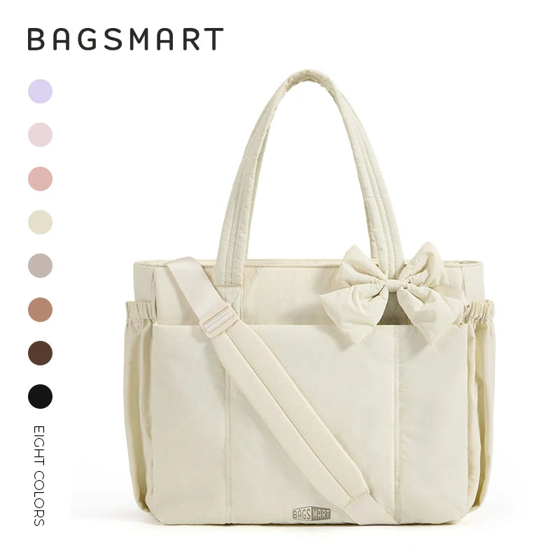 A cream-colored canvas tote bag with a bow detail and multiple pockets shown against a white background.